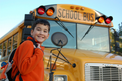 Smiling student in front of school bus.